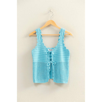 Light blue crochet top on a wooden hanger against a beige wall