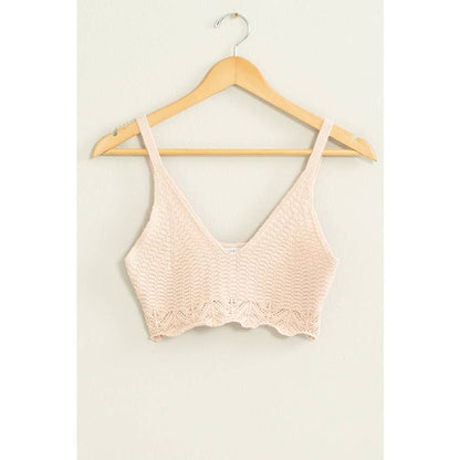 Pink bralette on a wooden hanger against a white background