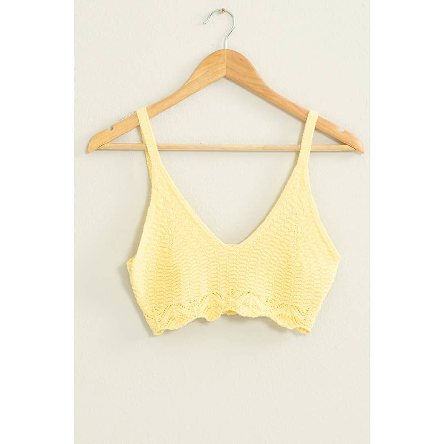 Yellow lace bralette on a wooden hanger against a light background
